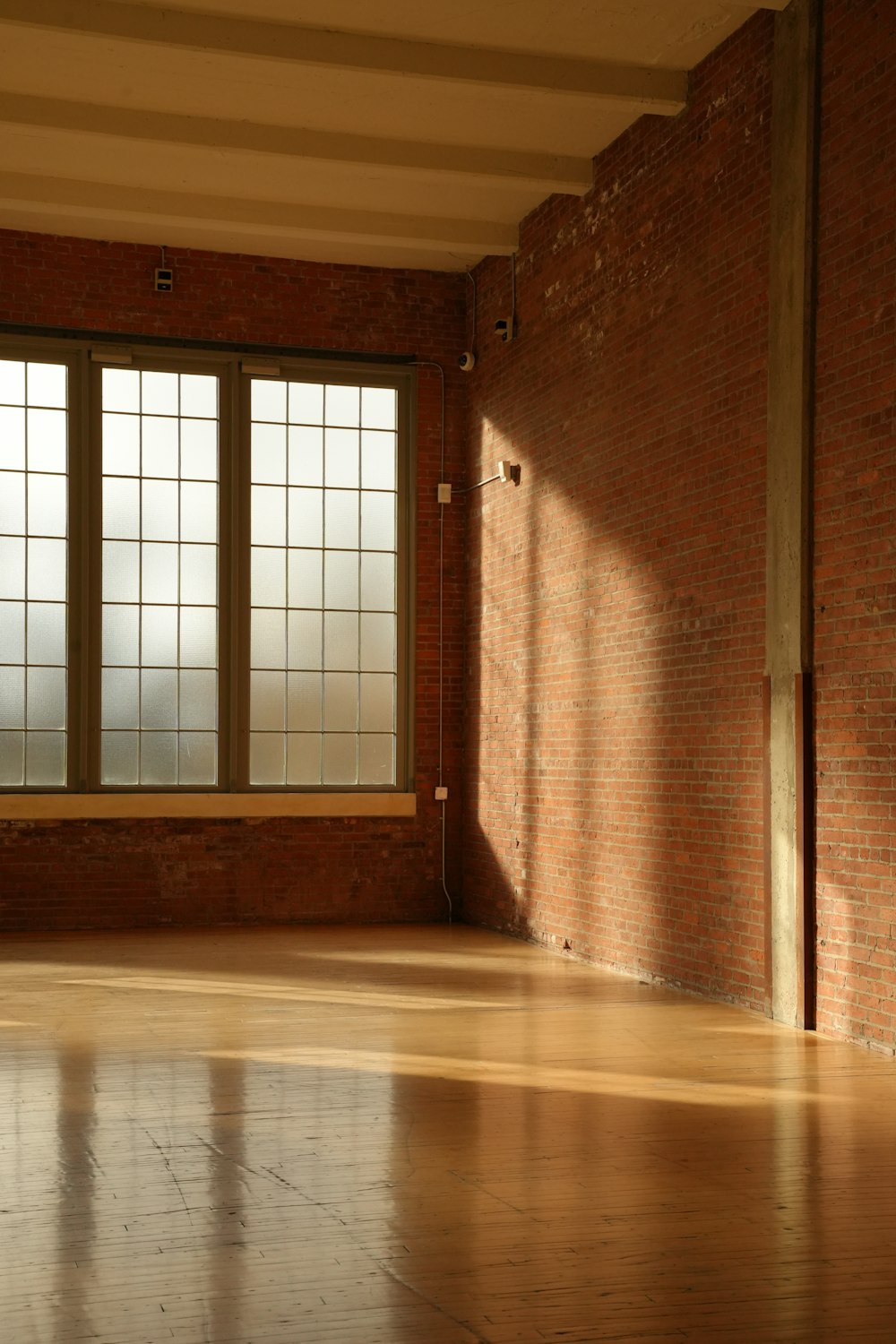 Sunlit studio space with wood floors and exposed brick